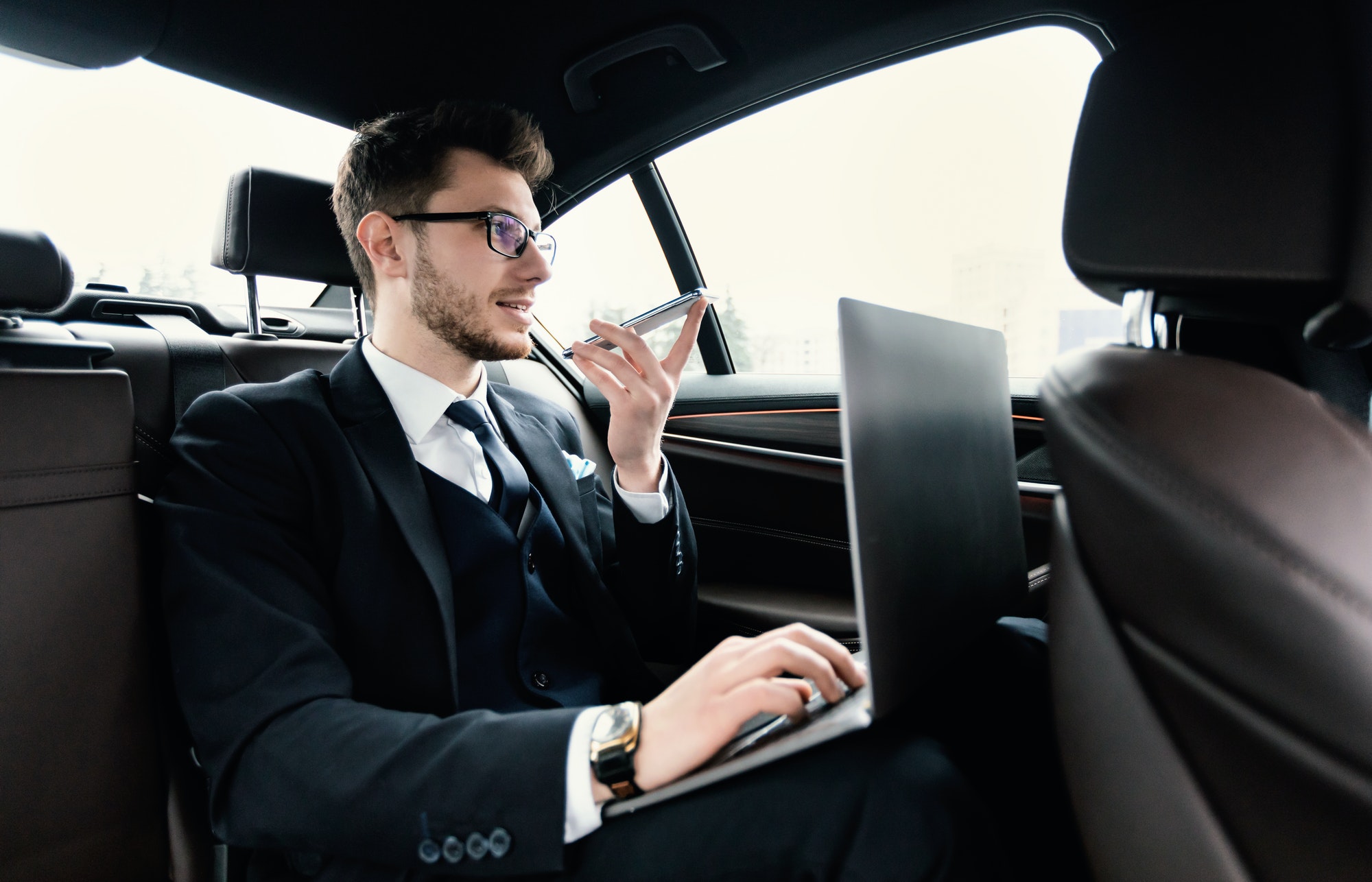 Young businessman talking on phone in taxi